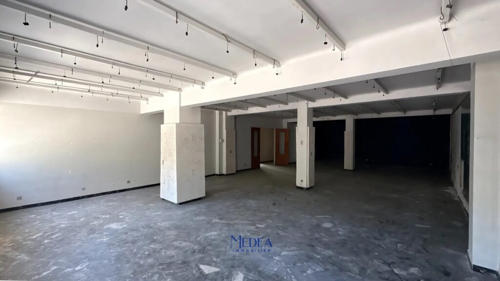 Espace commercial vide avec piliers et crochets au plafond