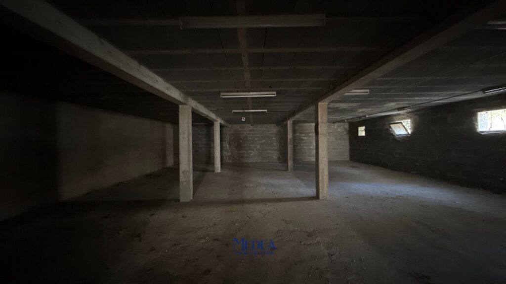 Sous-sol sombre avec piliers en béton et fenêtres sur le mur de droite