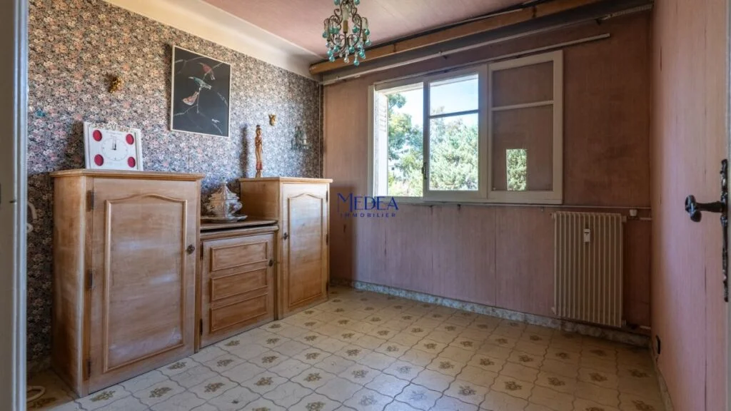 Chambre avec papier peint floral, meubles en bois et fenêtre