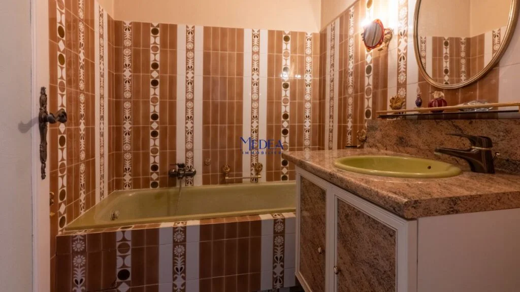 Salle de bain avec baignoire verte et lavabo sur meuble en marbre