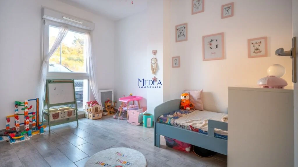 Chambre d'enfant avec lit bleu, chevalet, jouets et décorations murales