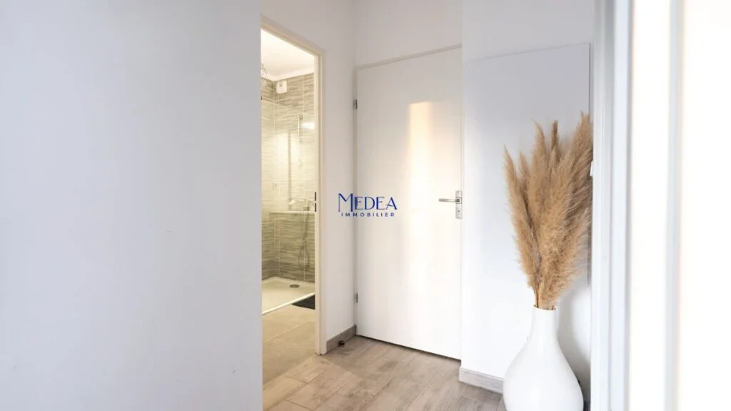 Couloir avec porte, douche et vase de pampas